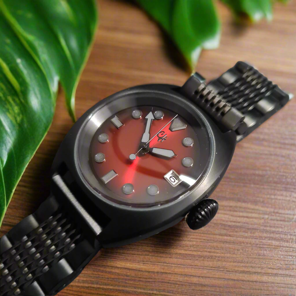 Wristwatch with a red face and black metal strap on a dark background