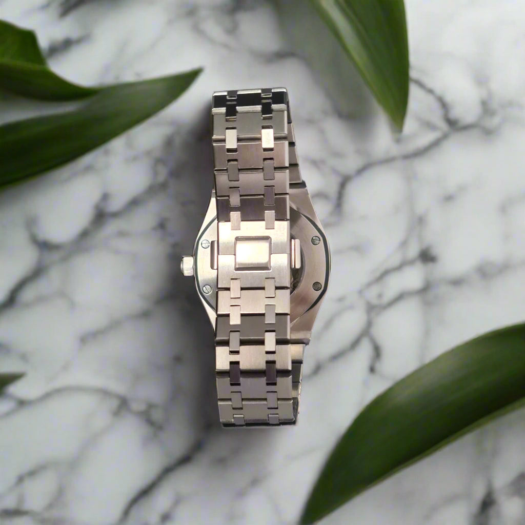 Silver watch on a marble surface with green leaves