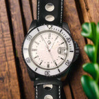Wristwatch with black leather strap and silver case on a dark background