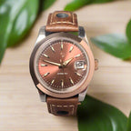 Wristwatch with brown leather strap and rose gold dial on a dark background