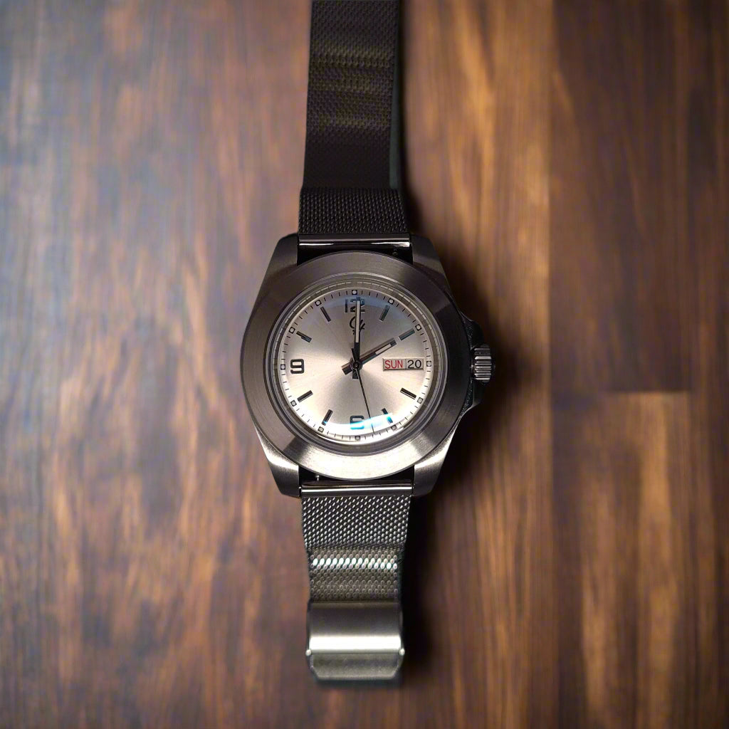 Silver watch with a mesh band on a black background
