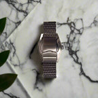 Silver watch with mesh band on a black background