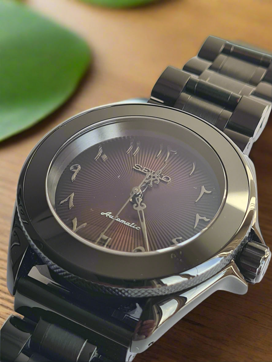 Close-up of a watch with a brown dial and metallic band on a table