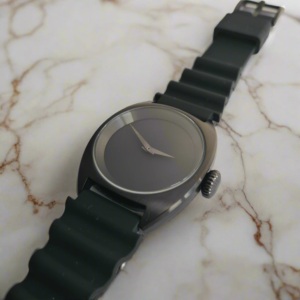 Black wristwatch with a textured strap on a marble bench top