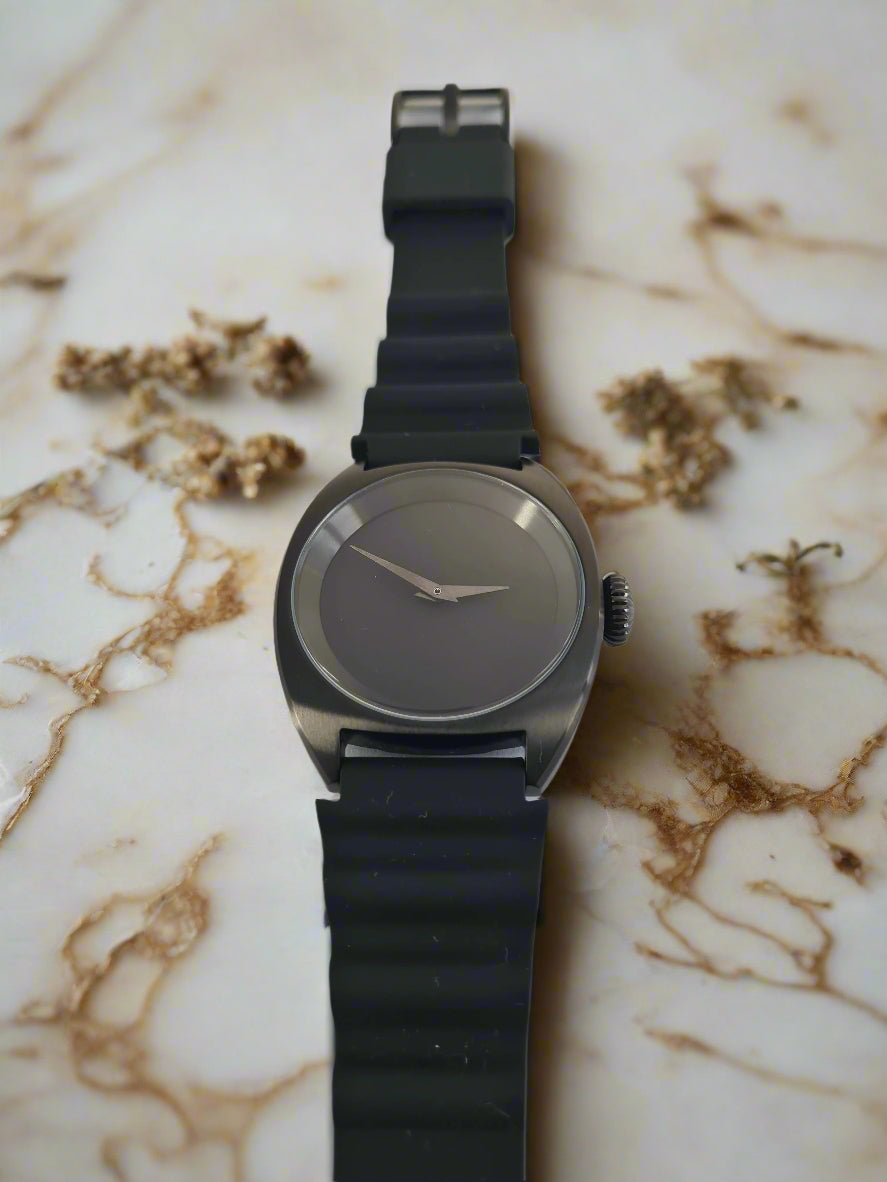 Black wristwatch with a metallic case on a light gray background