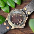 Wristwatch with a dark strap and brown dial on an oak table