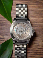 Silver watch with a detailed face on a table