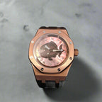 Rose gold watch with a pink face on a grey background