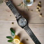 Wristwatch with a dark leather strap on a gray background