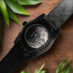 Black wristwatch with visible mechanical components on a dark background