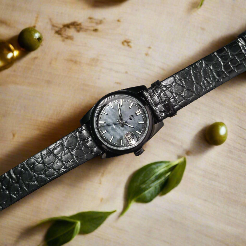 Black wristwatch with a textured strap on a dark surface