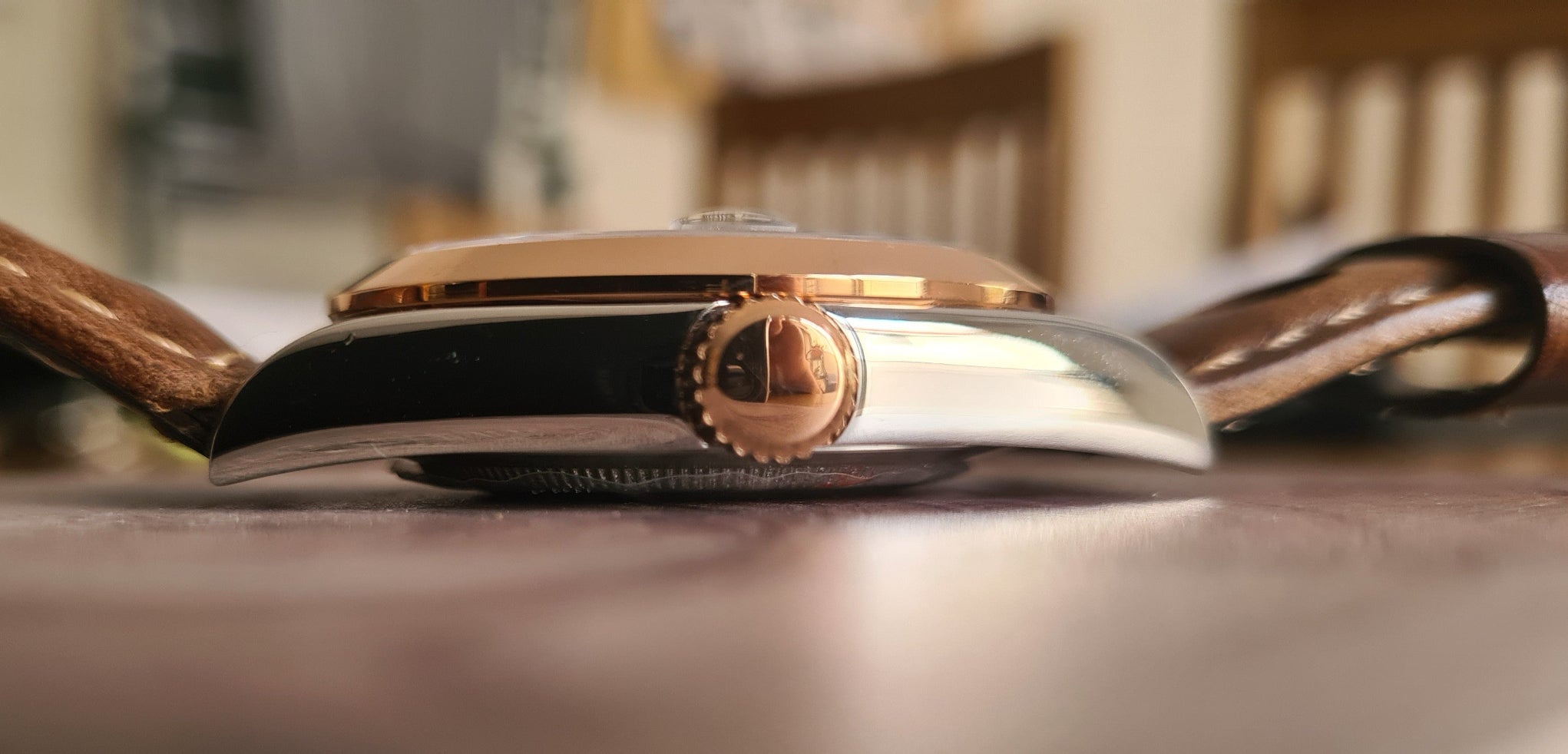 Close-up of a gold and silver watch on a wooden surface with blurred background