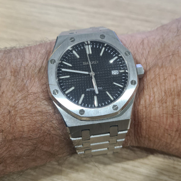 Silver Seiko watch on a wrist with a wooden background