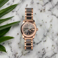Rose gold watch with black face on a dark gray background