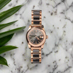 Rose gold watch with black face on a dark gray background