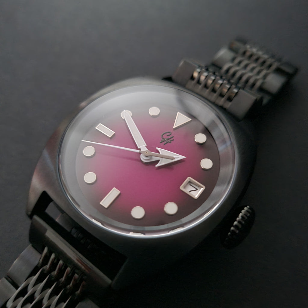 Watch with a pink face and metal strap on a dark background