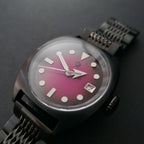 Watch with a pink face and metal strap on a dark background