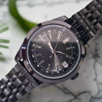 Black wristwatch with a metallic band on a light gray background