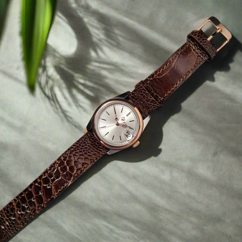 This watch features a textured silver dial with a subtle sunray pattern, accented by applied rose gold indices and slender rose gold hands, including a date window at 3 o'clock. Encased in a polished rose gold stainless steel case, it pairs seamlessly with a rich dark brown crocodile-patterned leather strap, offering a harmonious blend of luxury and durability. Powered by the reliable NH35 automatic movement, it’s designed for those who value classic artistry and dependability