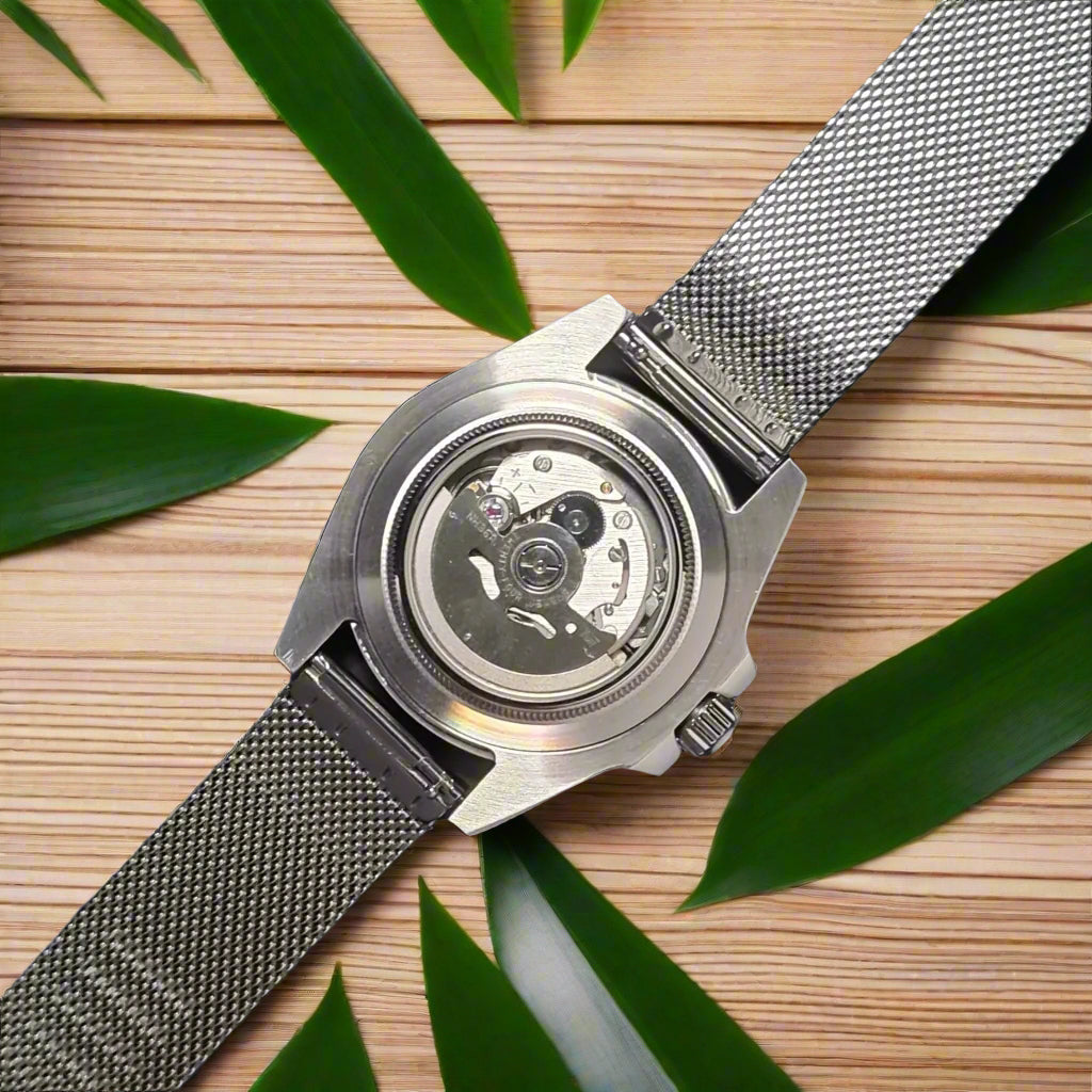 Silver watch with mesh band on a dark gray background