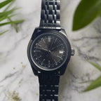 Black wristwatch with a detailed face on a white background