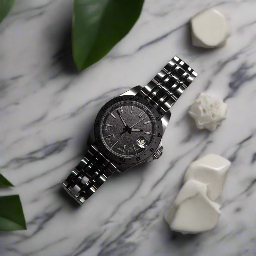 Silver watch with a dark face on marble table