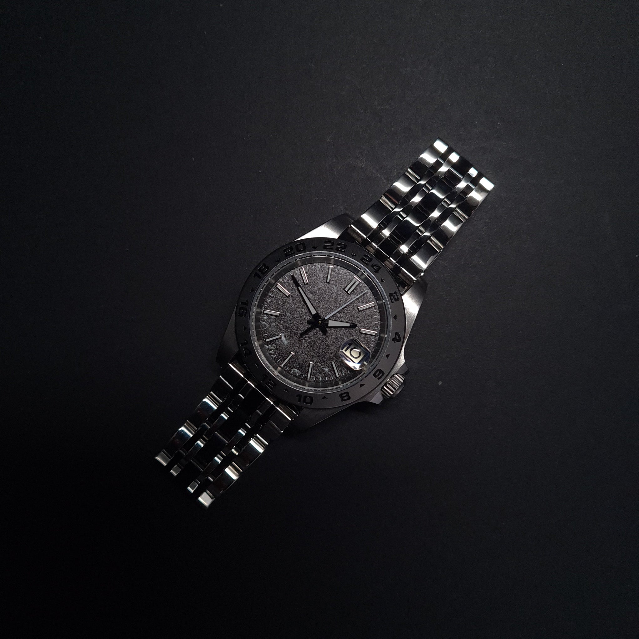 Silver watch with a dark face on a black background