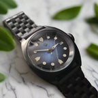 Black wristwatch with a dark face on a gray background