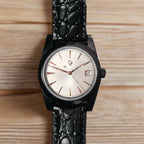 Black wristwatch with a textured strap on a wooden surface