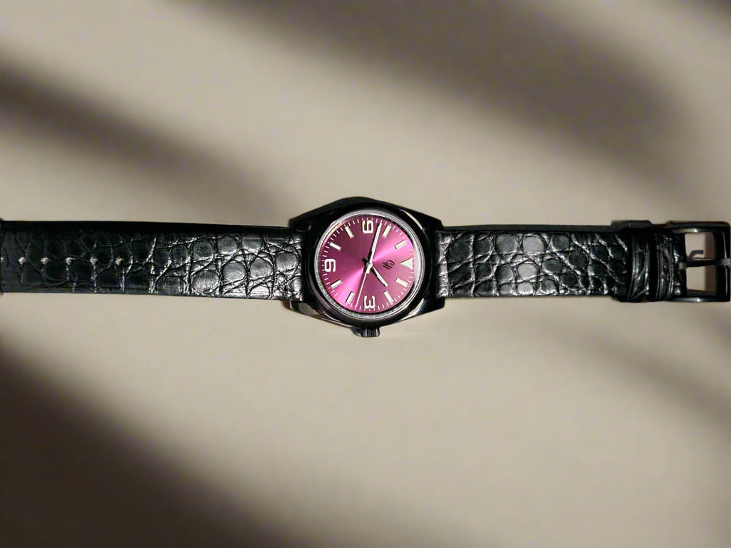 Watch with a pink face and black strap on a dark background
