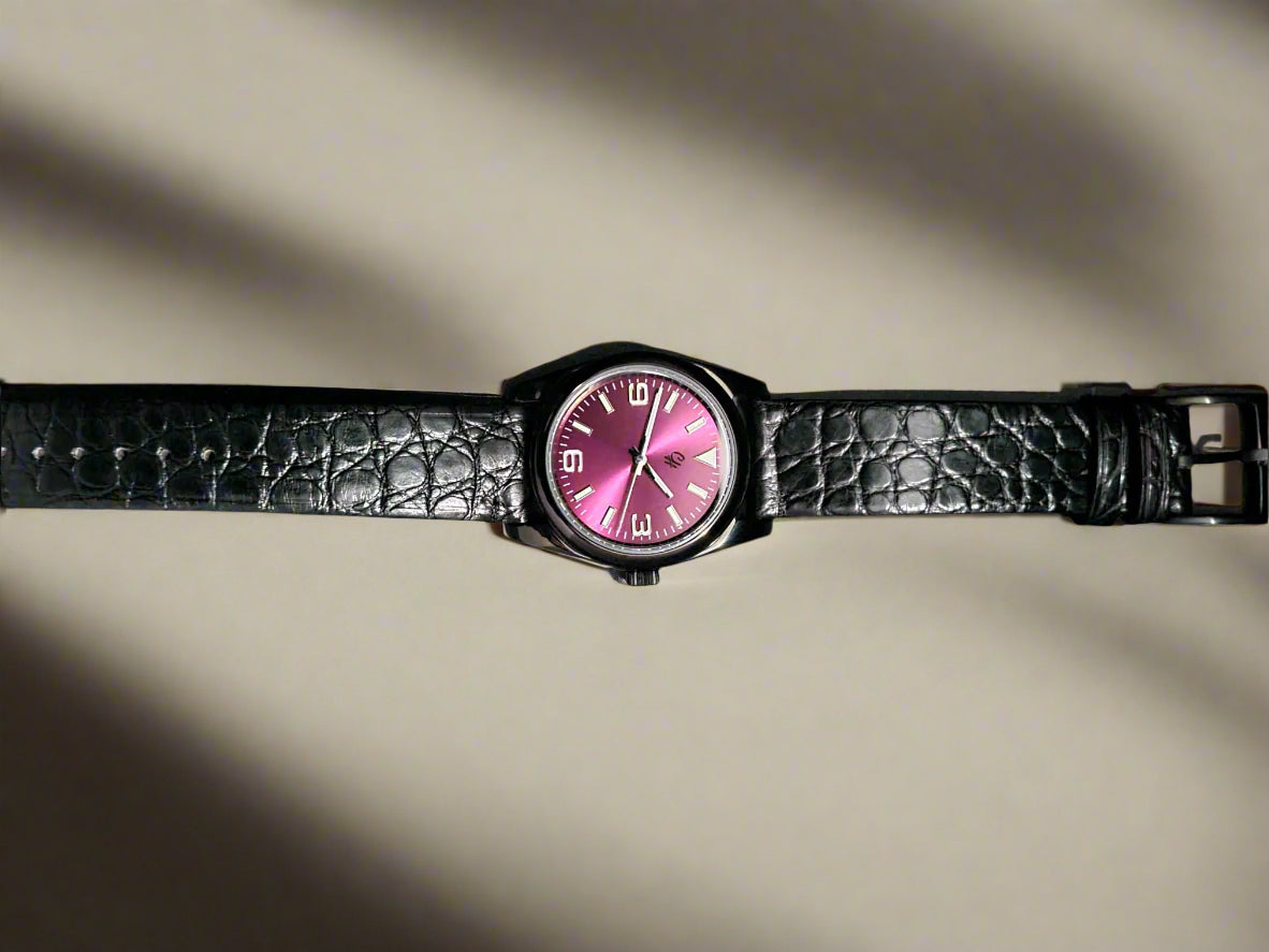 Watch with a pink face and black strap on a dark background