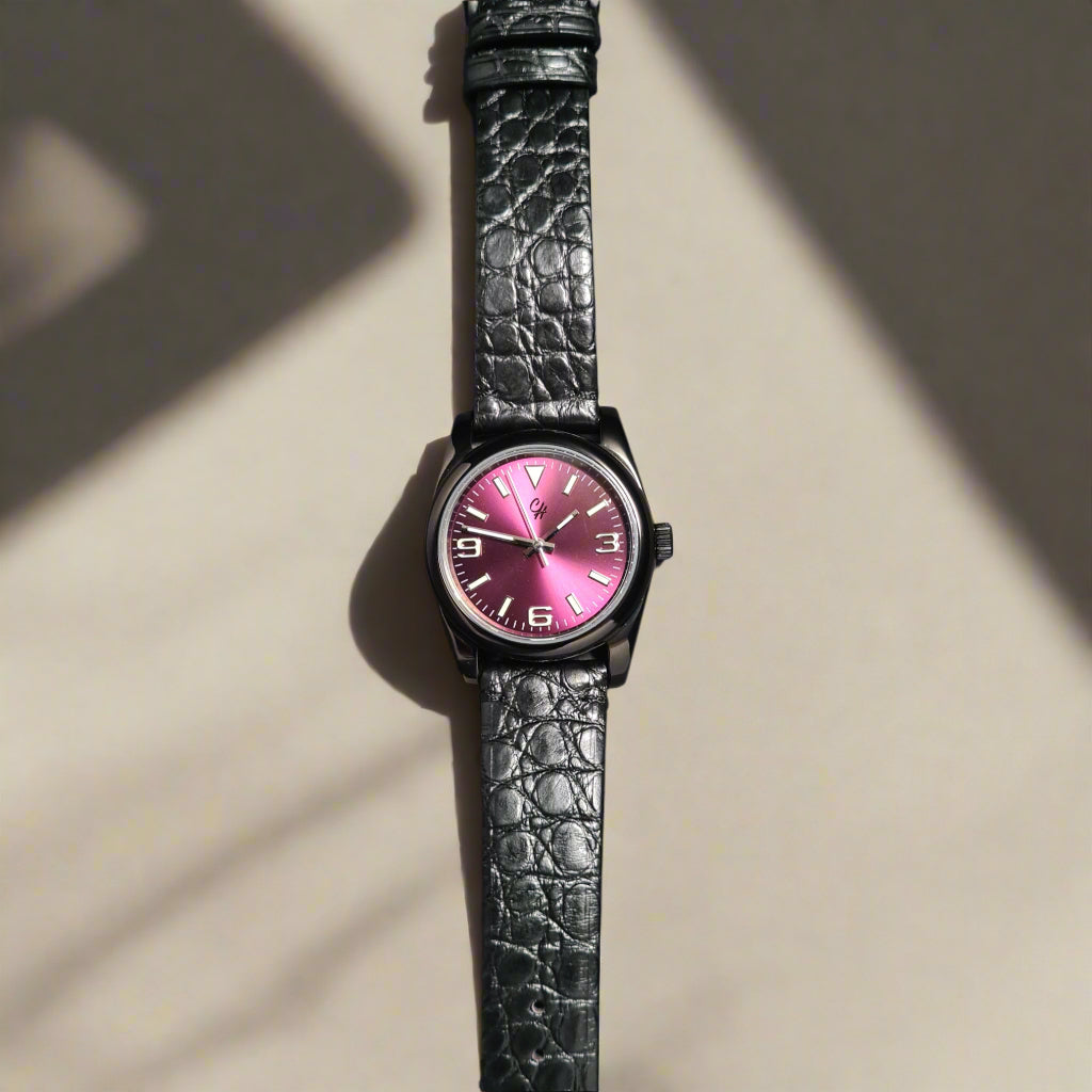 Watch with a black strap and pink face on a dark gray background