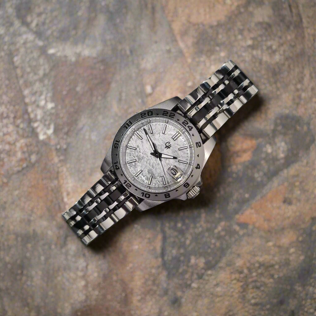Silver wristwatch with a detailed face on a dark gray surface