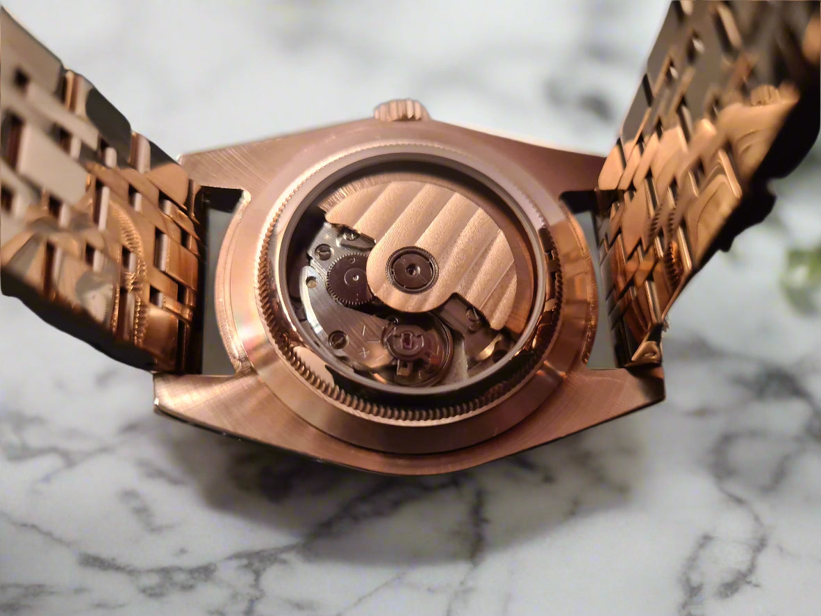 Rose gold watch with open face revealing mechanical components on a marble background