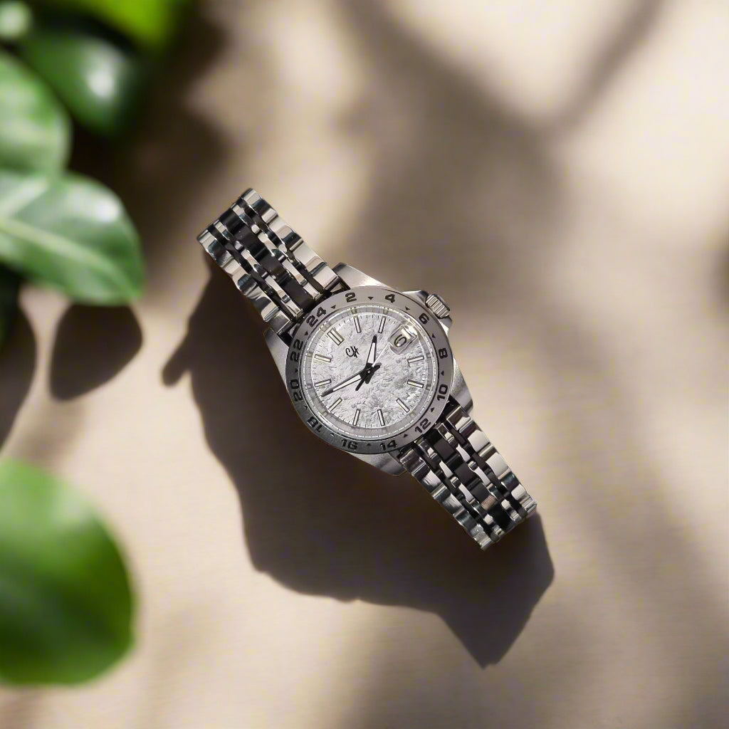 Silver watch with a textured band on a dark gray background