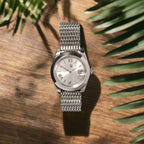 Silver wristwatch with mesh band on a dark gray background