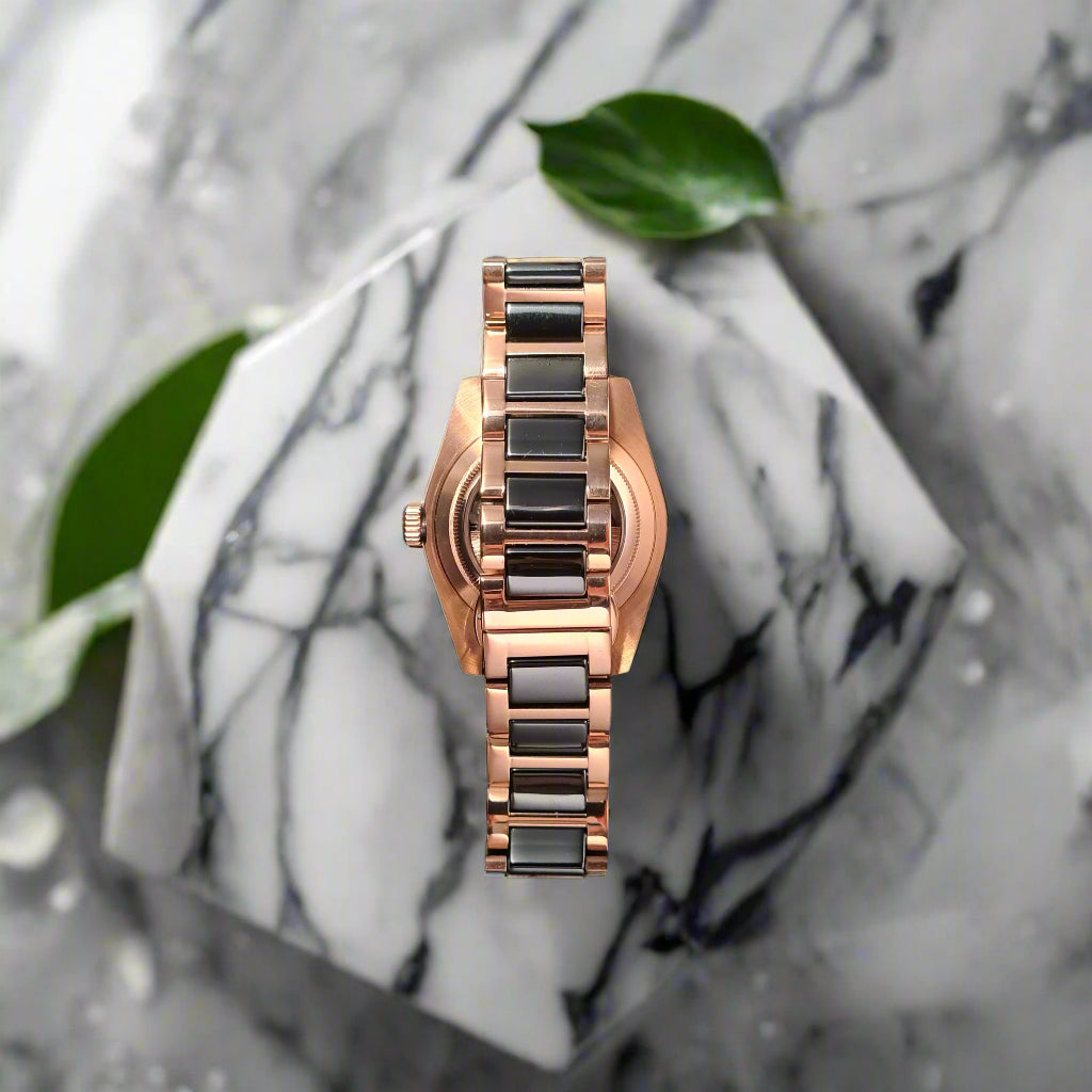 Rose gold watch with black band on a dark gray background