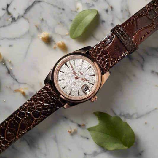 Watch with brown leather strap on a dark surface