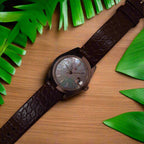 Wristwatch with brown leather strap on timber table