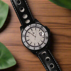 Watch with black leather strap and white face on a dark background