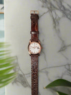 Watch with brown textured strap on a dark background